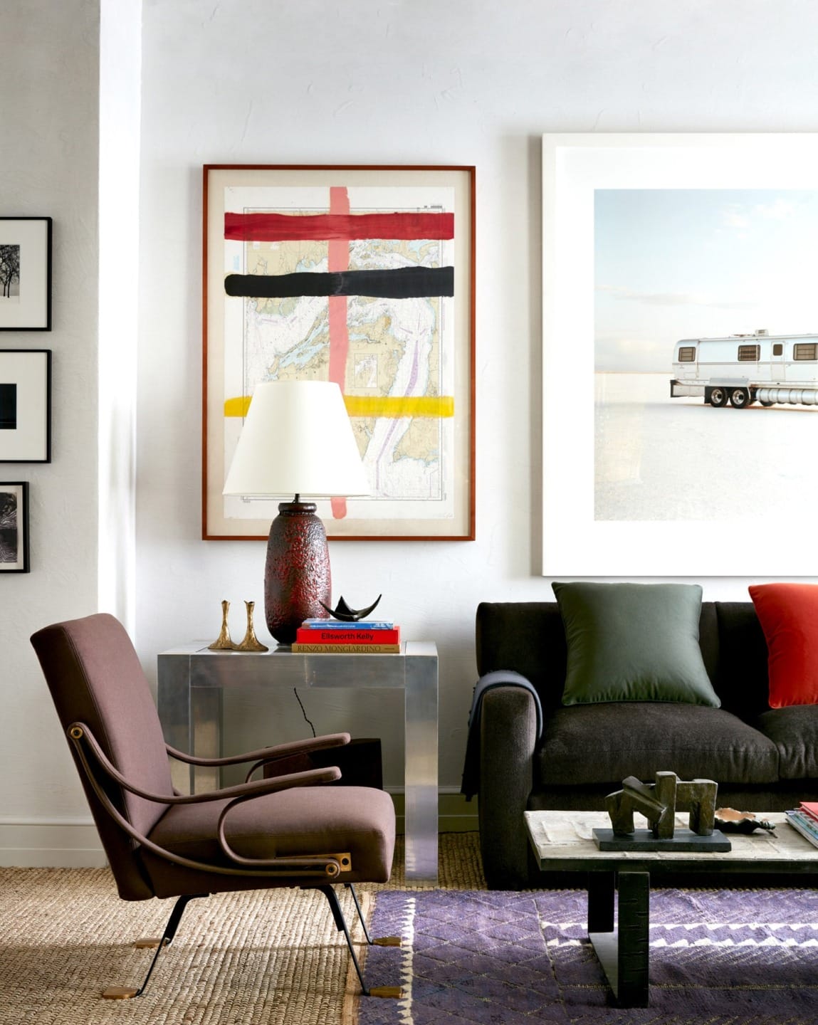 Modern living room with abstract art, brown armchair, black sofa, and a table lamp on a side table.