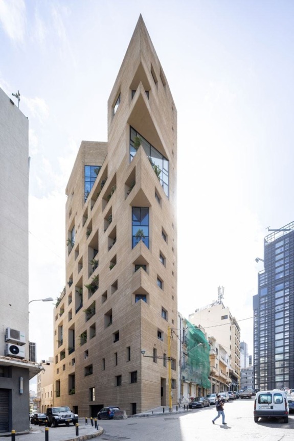 Unique multi-story building with geometric windows and sharp angles on a city street corner.