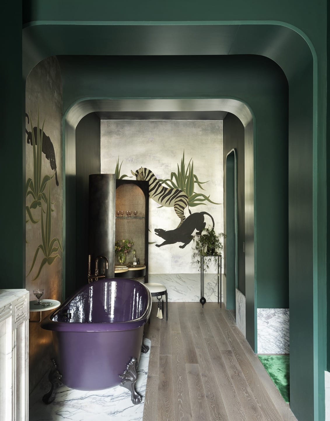 Luxurious bathroom with a dark green interior, purple clawfoot tub, and artistic animal-themed wall mural.