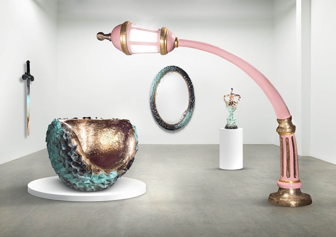 Contemporary art installation in a gallery with unique sculptures and wall-mounted pieces displayed on pedestals and walls.