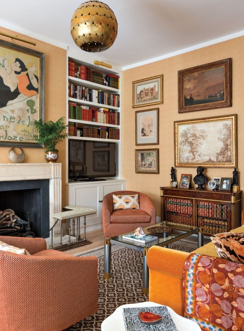 Cozy living room with vibrant art, bookshelves, patterned rugs, and an eclectic mix of chairs and decor.