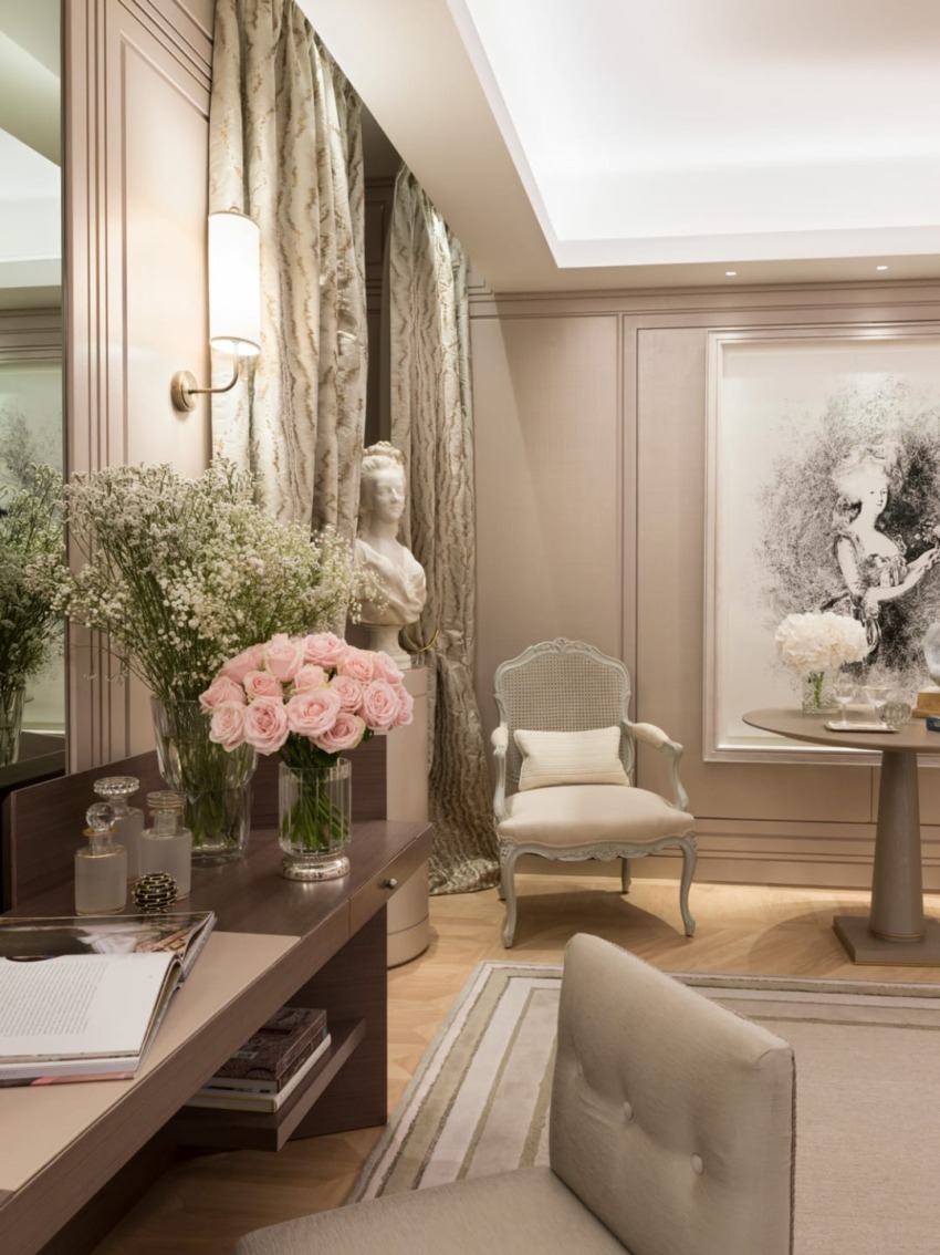 Elegant room with floral decor, artwork, and sophisticated seating featuring a classical bust and a vase of pink roses.