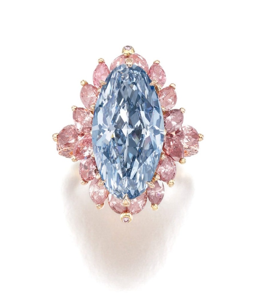Oval blue gemstone ring with pink diamond petals set in gold, creating a floral design.