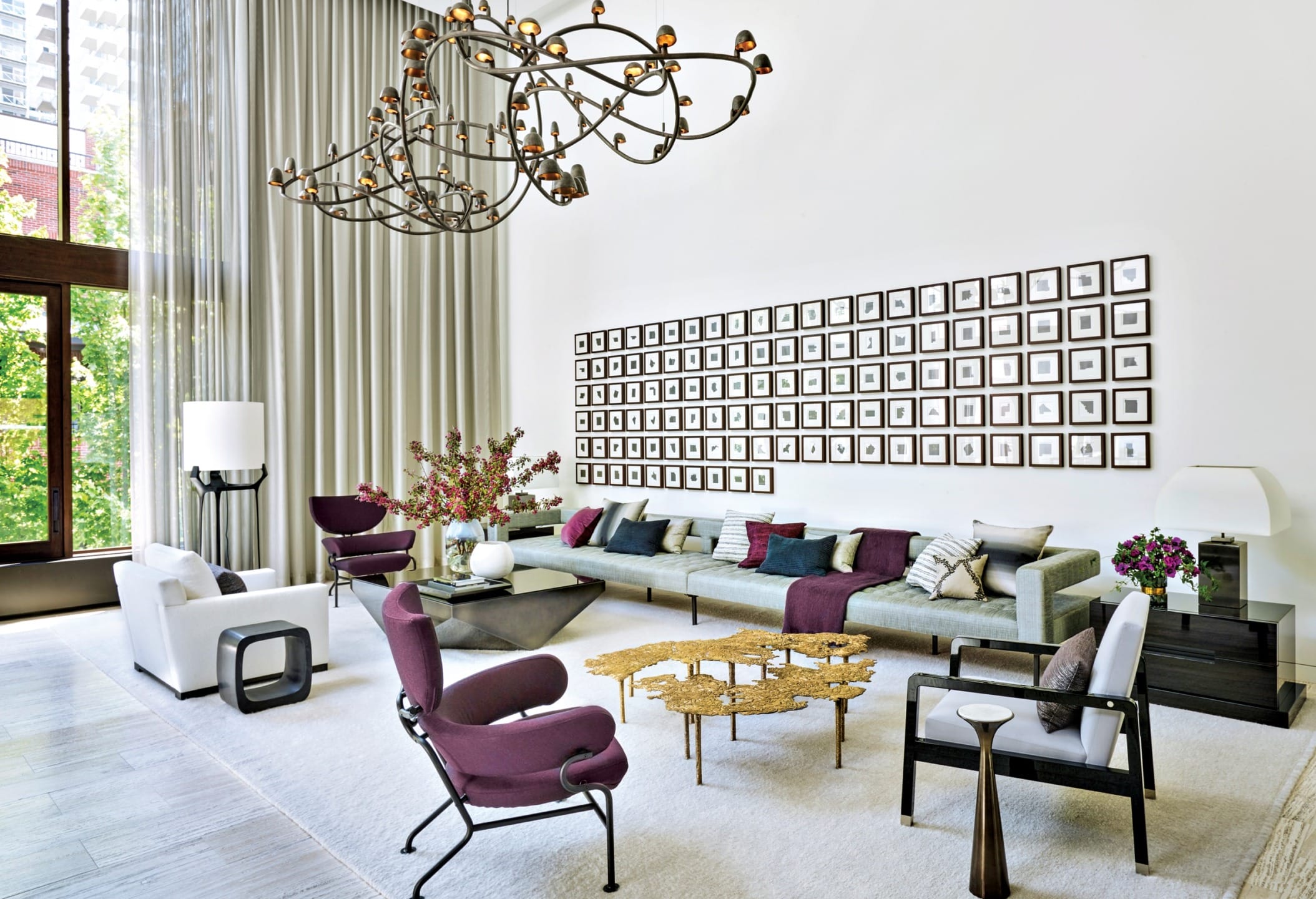 Modern living room with high ceilings, large windows, elegant chandelier, and contemporary furniture in neutral tones.