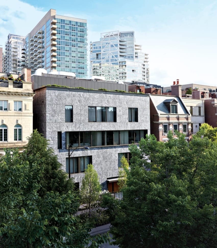 Modern cityscape with contemporary and historic buildings surrounded by greenery, under a clear blue sky.