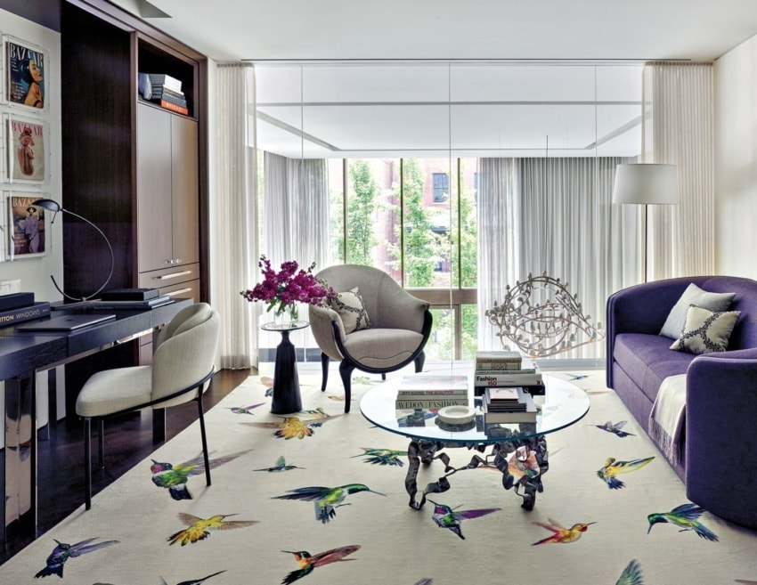 Modern living room with stylish furniture, large window, colorful bird-patterned rug, glass table, and decorative elements.