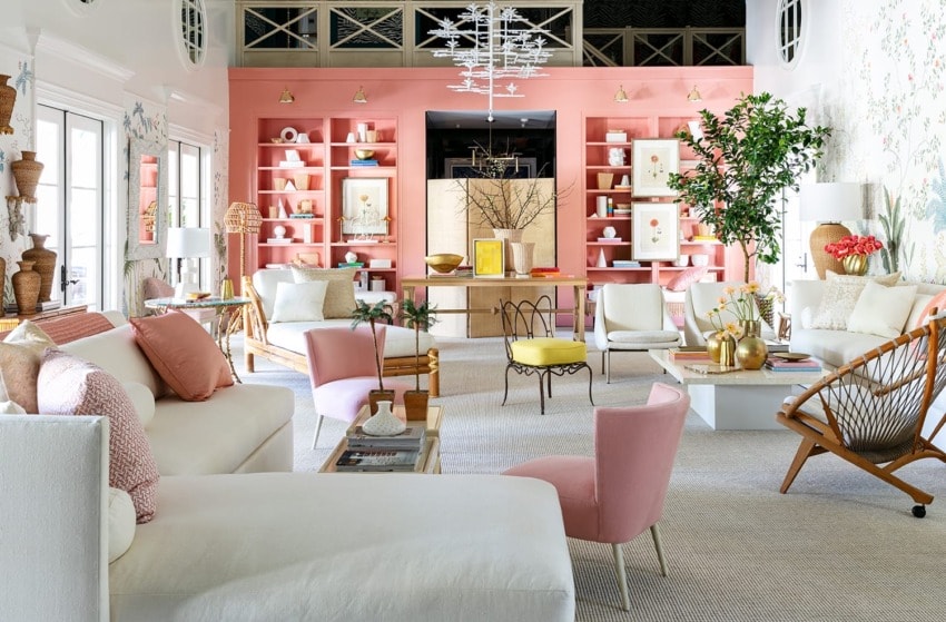 Colorful living room with white couches, pink accent chairs, and decorative shelves filled with various vases and plants.