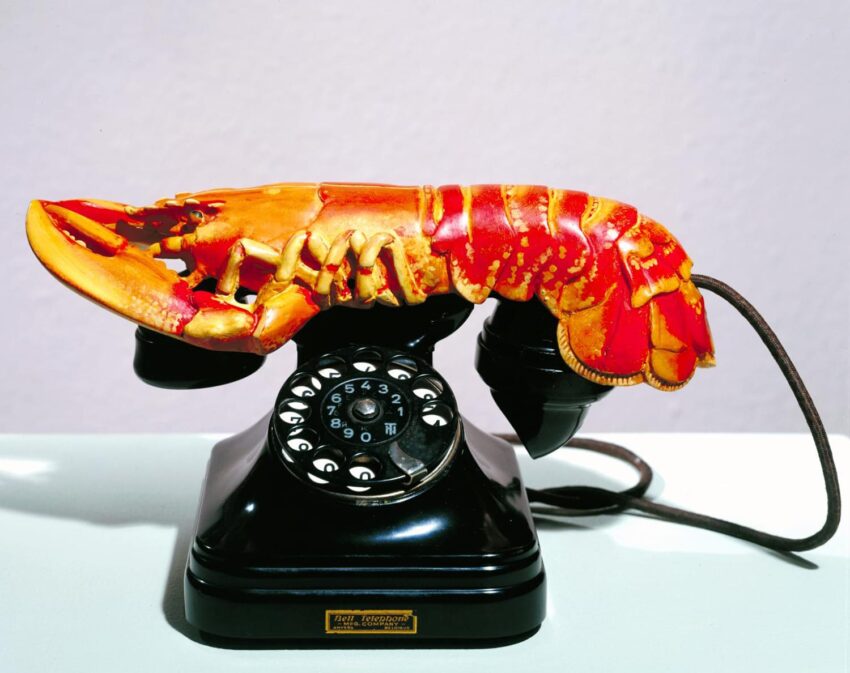 Vintage rotary phone with a colorful lobster-shaped handset displayed on a flat surface.