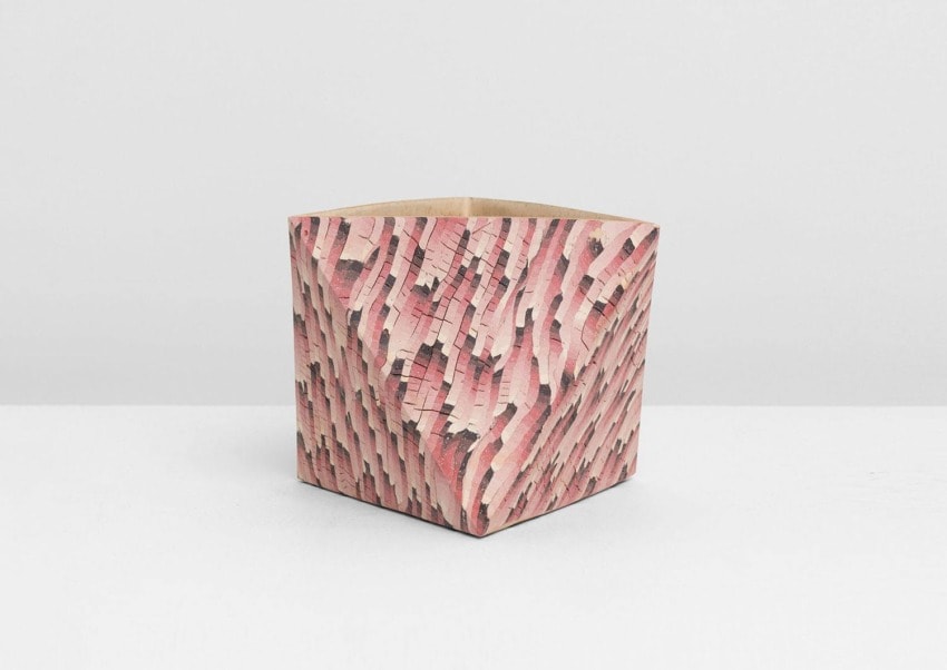 Wooden vase with a pink and textured mosaic design stands on a white surface against a light gray background.