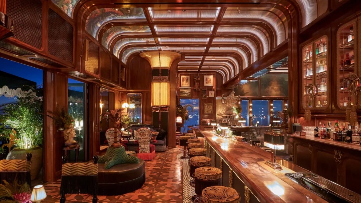 Luxurious bar interior with warm lighting, ornate ceiling, plush seating, and decorative elements, creating an inviting atmosphere.