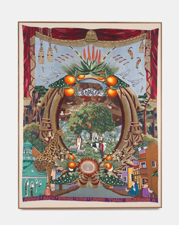 Colorful tapestry featuring animals, buildings, and trees surrounding a central oval with decorative fruits and fabric details.