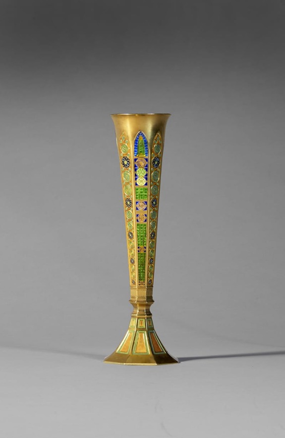 Tall brass vase with intricate colorful enamel patterns on a gray background.