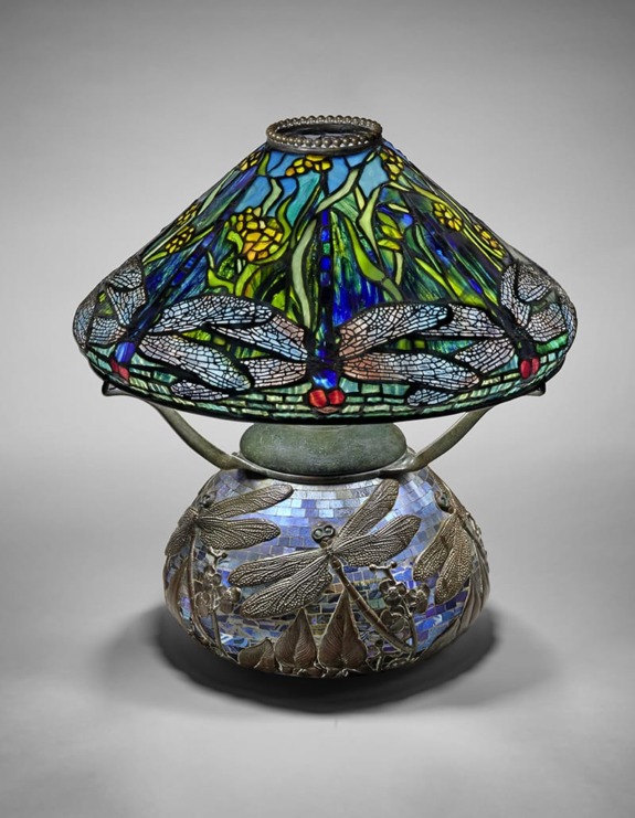 Stained glass lamp with intricate dragonfly and floral designs on the shade, set on a detailed decorative base.