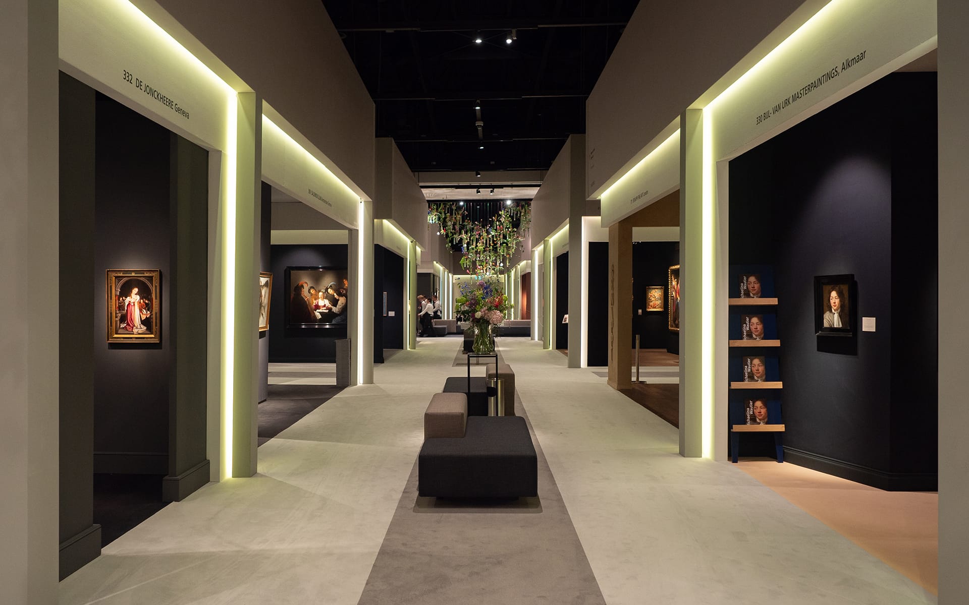 Art gallery hallway with illuminated frames and modern seating, showcasing various paintings in a contemporary design setting.