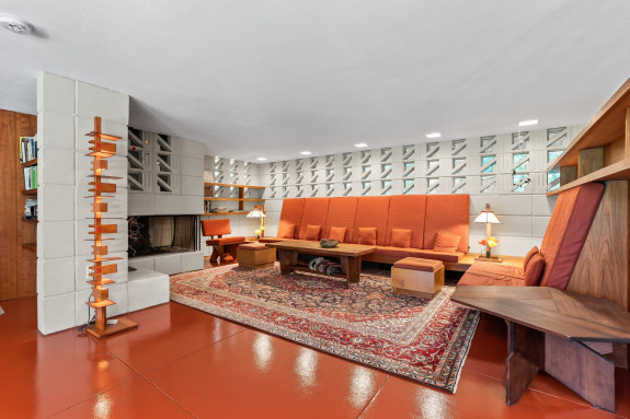 Mid-century modern living room with orange seating, geometric wall design, and a decorative rug.