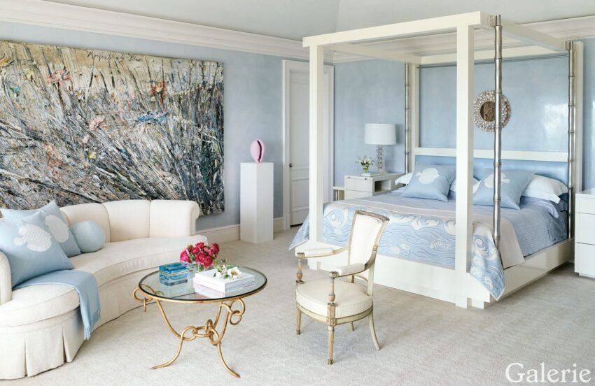 Elegant bedroom with a canopy bed, abstract artwork, beige sofa, and glass coffee table with flowers.