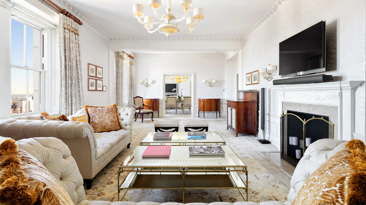 Luxurious living room with elegant decor, chandelier, coffee table, and a large window offering a stunning city view.