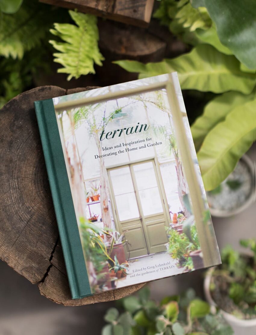 Book titled "Terrain: Ideas and Inspiration for Decorating the Home and Garden" on a table with surrounding plants.