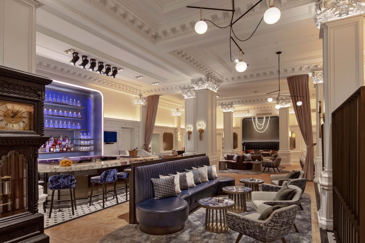 A luxurious hotel lobby with elegant seating, decorative ceiling, and a well-stocked bar.