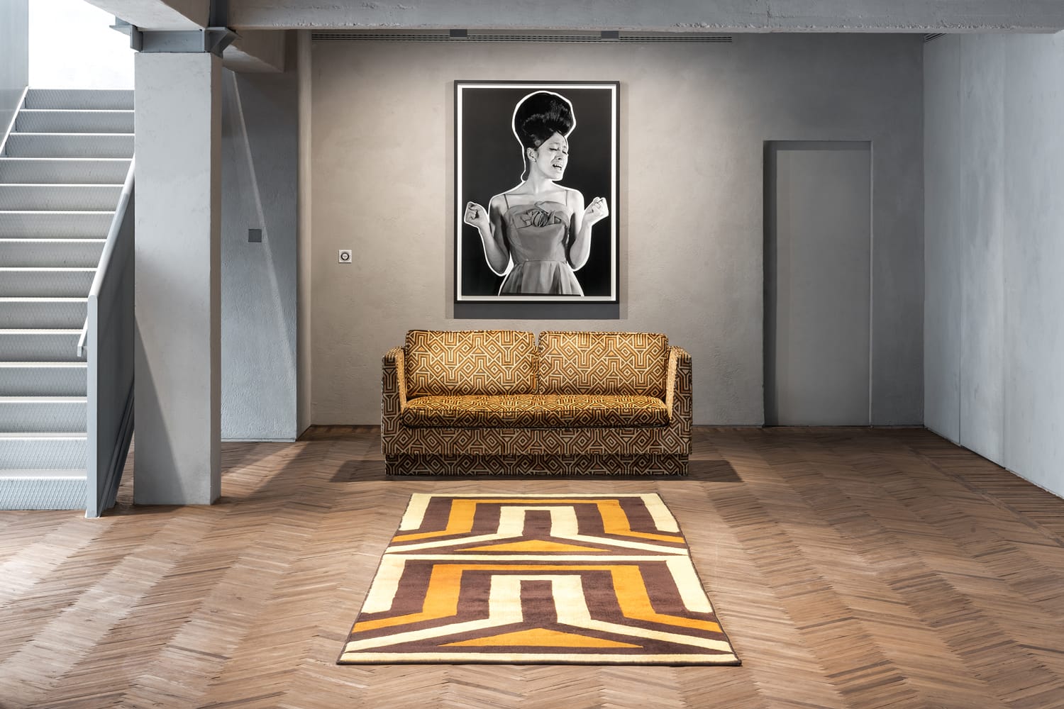 Vintage sofa and geometric rug in modern room with black-and-white artwork on wall.