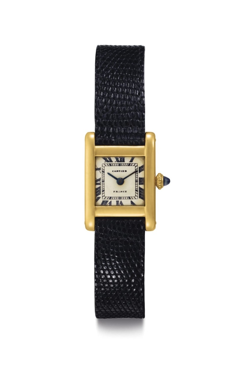 Vintage gold watch with rectangular face, black leather strap, Roman numerals, and a sapphire cabochon crown.