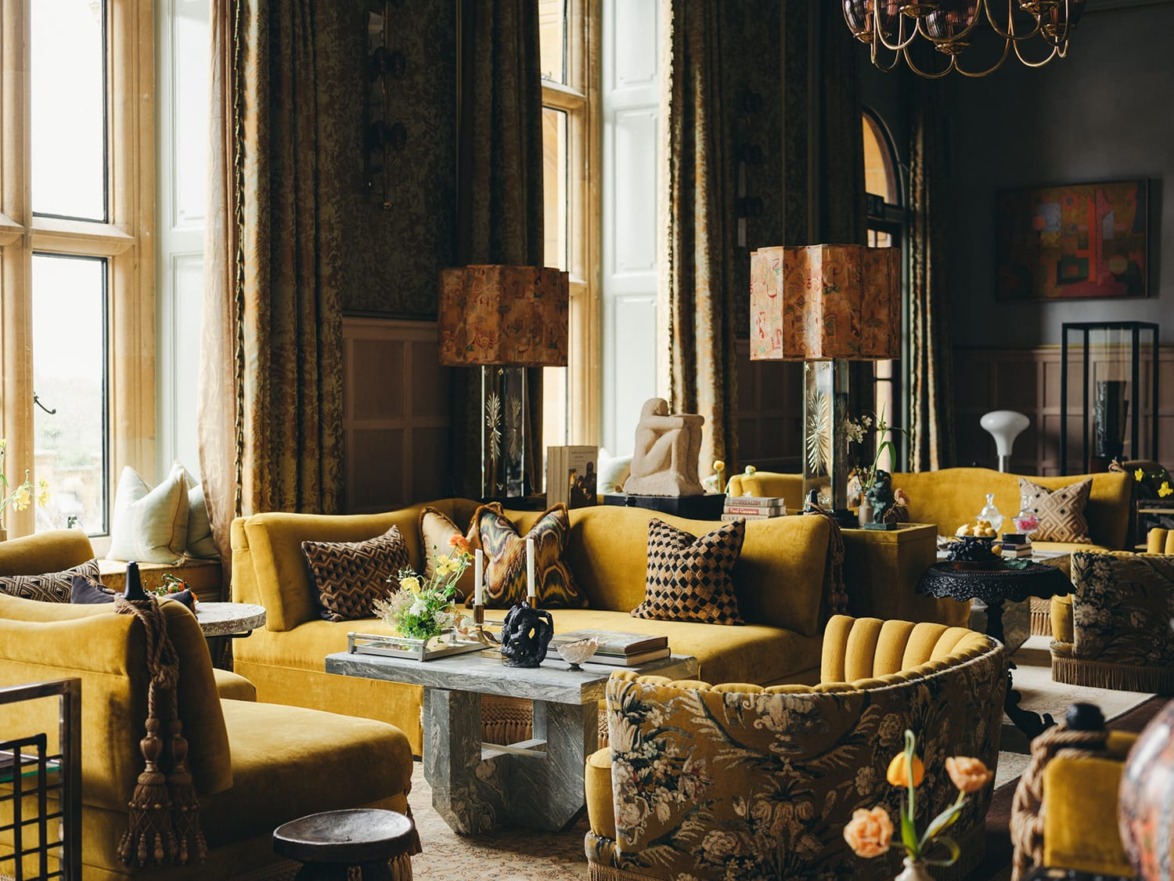 Elegant living room with yellow sofas, patterned cushions, large windows, and stylish decor elements.