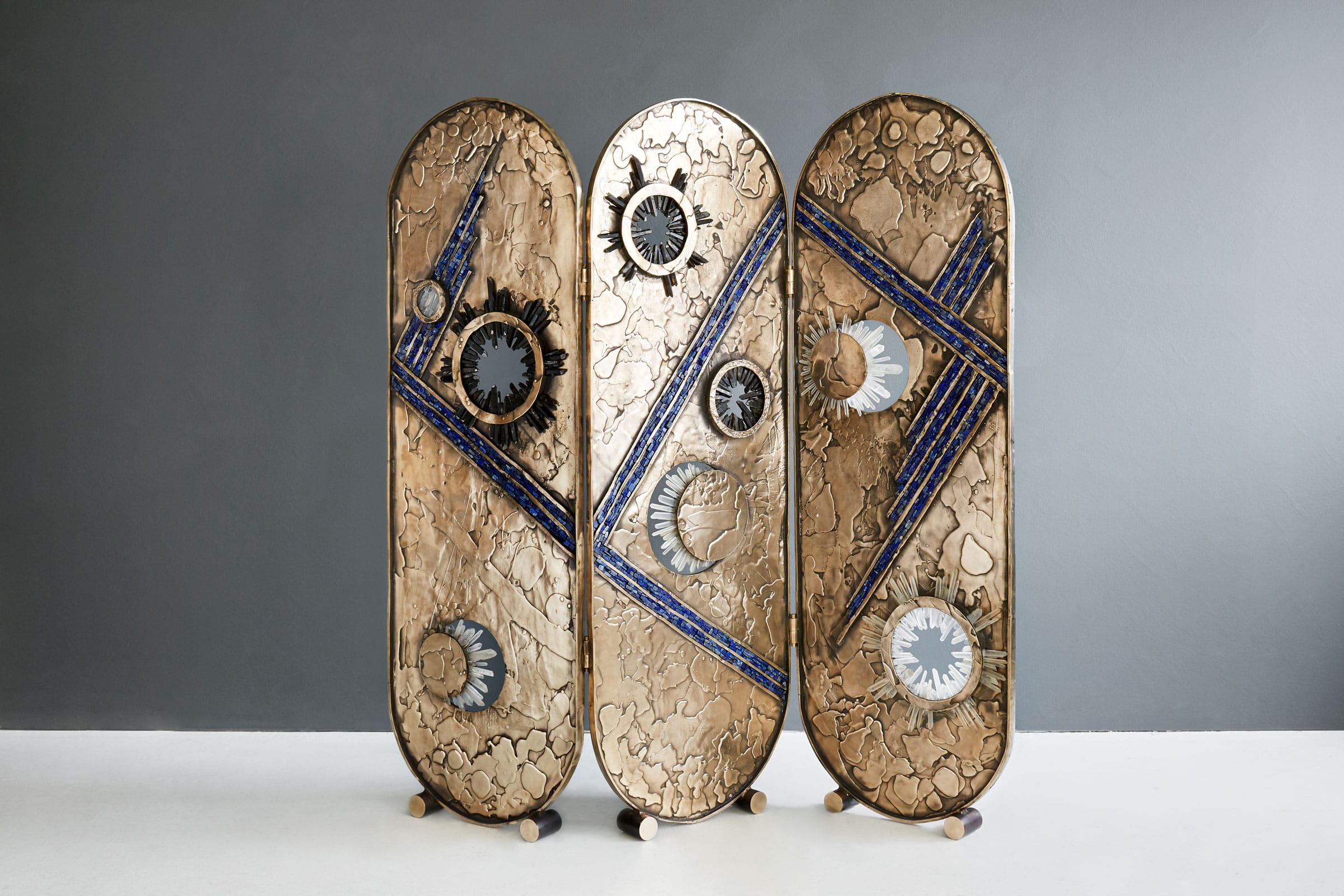 Three artistic skateboard decks with unique abstract designs and gears against a gray background.