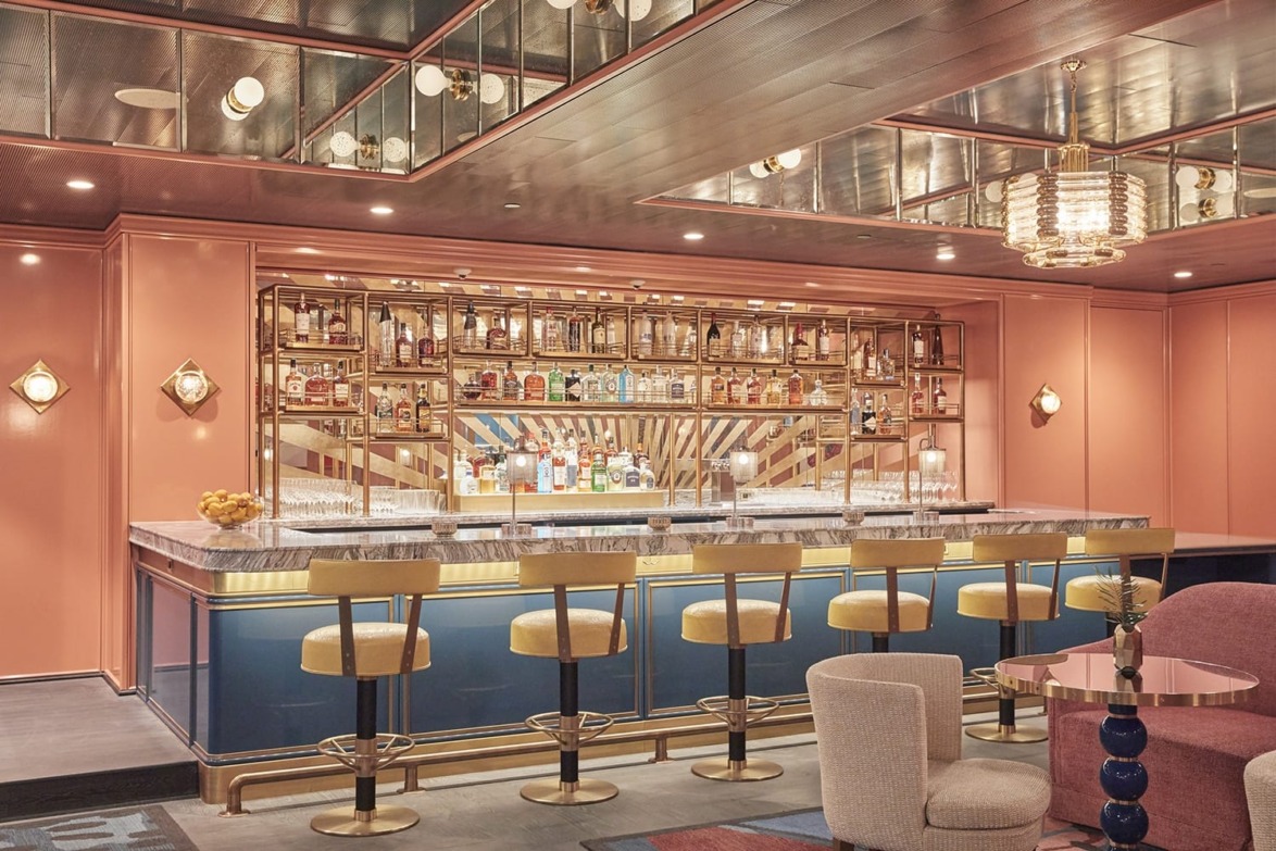 Stylish modern bar interior with plush seating, illuminated shelving showcasing various bottles, and chic lighting fixtures.