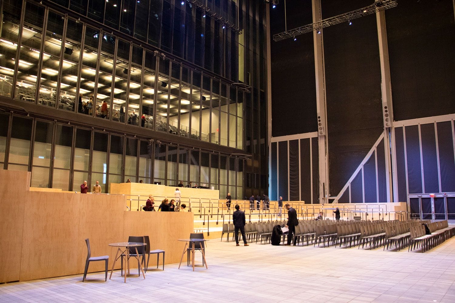Spacious modern auditorium with rows of seating, large windows, and a towering ceiling in an empty event hall.
