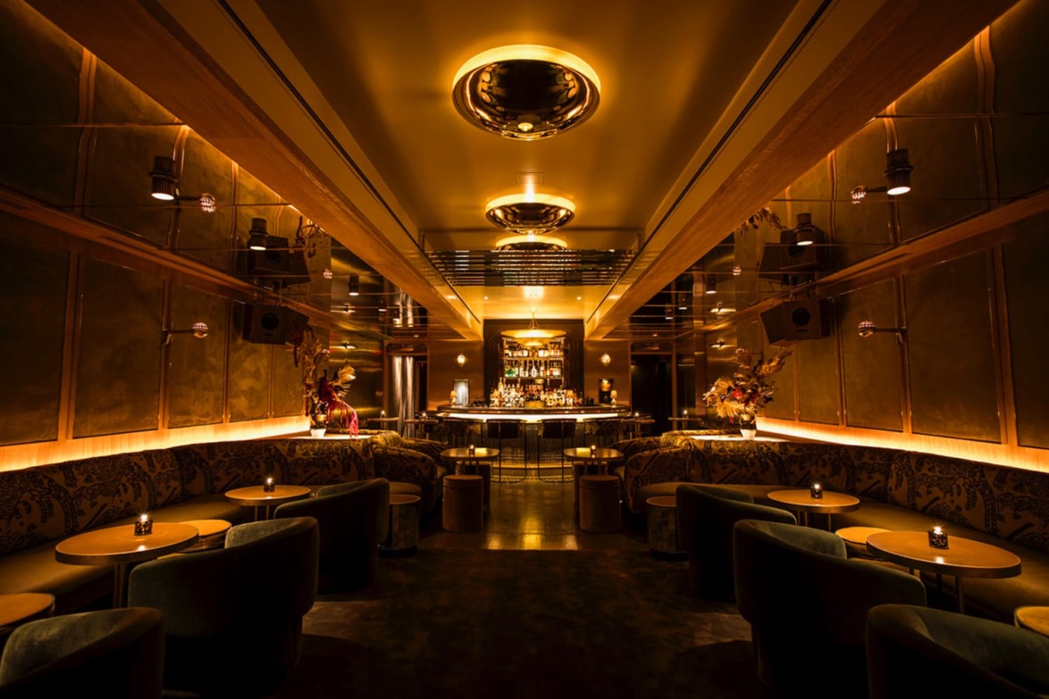 Dimly lit, elegant bar with plush seating and ambient lighting creating a cozy, luxurious atmosphere.