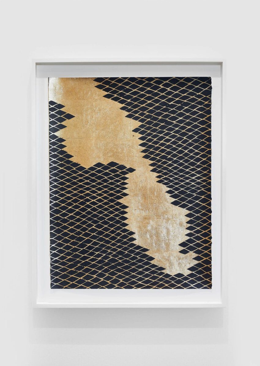 Abstract artwork with gold and black pattern, featuring geometric diamond shapes in a white frame against a plain background.