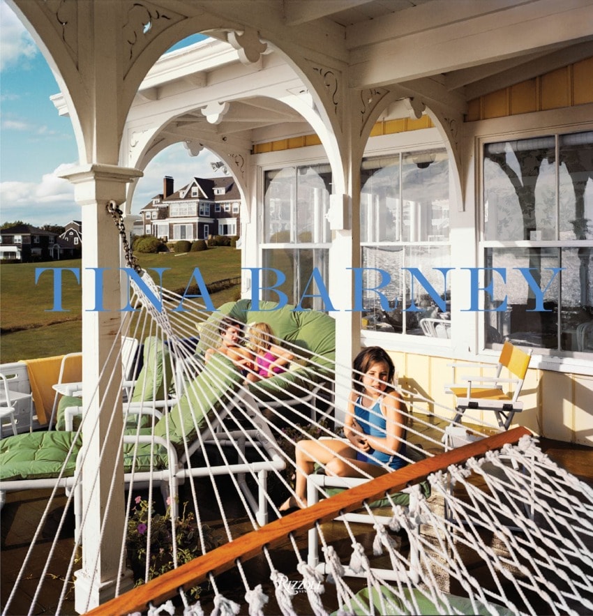 People relaxing on a green patio with colorful chairs and a hammock under a sunny sky.