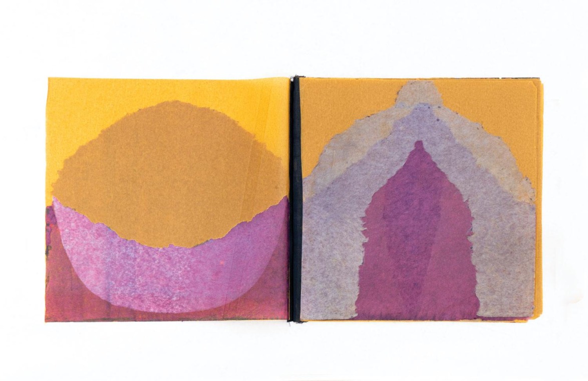 Abstract painting with pink, purple, and brown shapes on an open notebook against a white background.