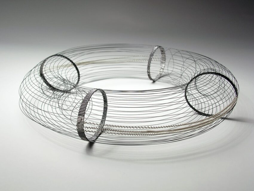 Wire art sculpture with circular rings and intricate weaving design displayed on a plain background.