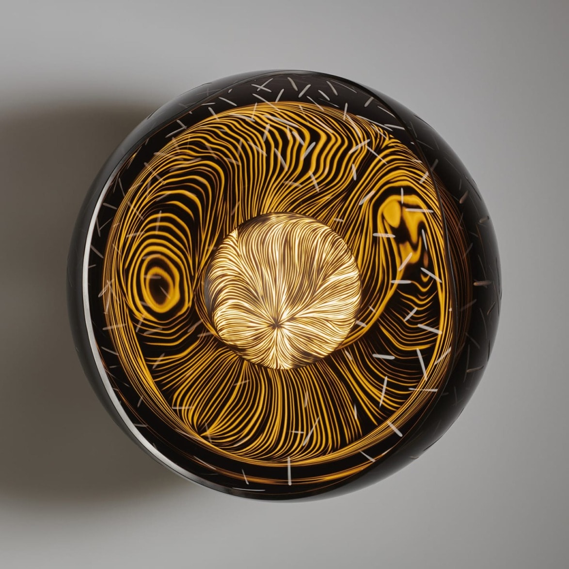 Overhead view of a decorative black and gold glass bowl with intricate swirling patterns and textures.