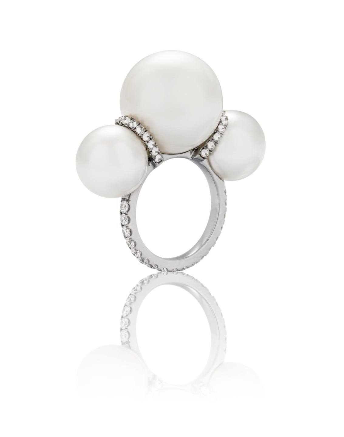 Silver ring with three large pearls and small crystals on a white background, reflecting the elegant design.