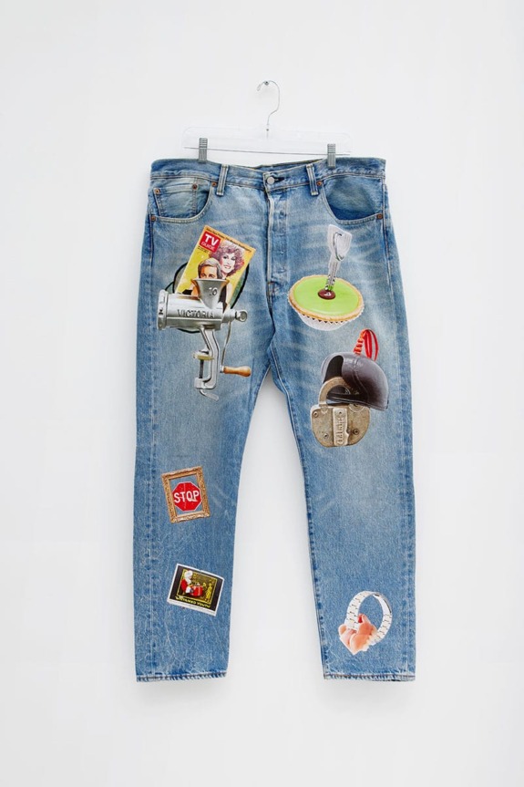 Vintage blue jeans decorated with eclectic retro items like toys, a lock, and a TV magazine hanging on a clear hanger.