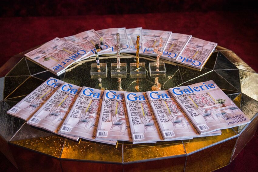 Magazines titled "Galerie" arranged in a circular pattern on a reflective golden table.