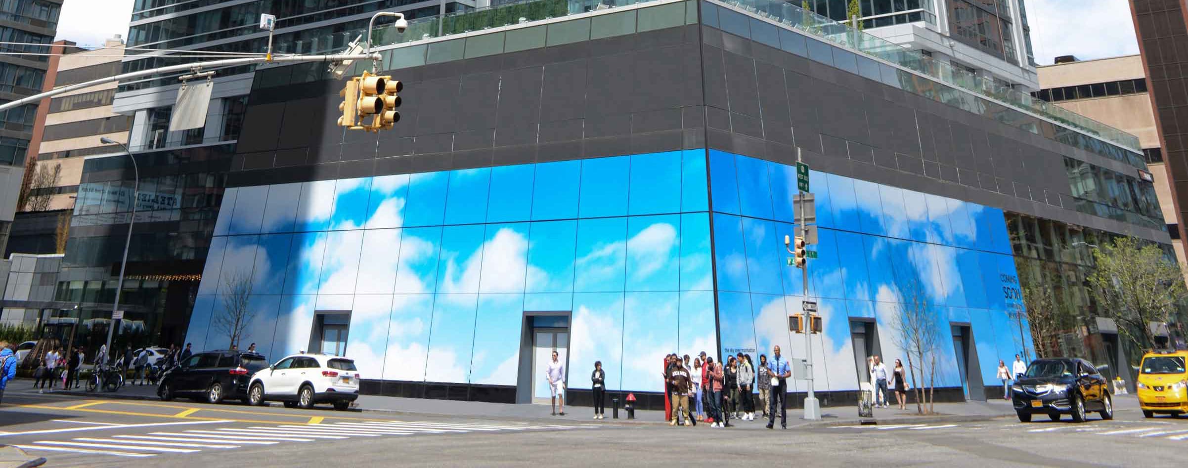 Street scene with people, cars, and a building featuring a large sky-themed mural with clouds.