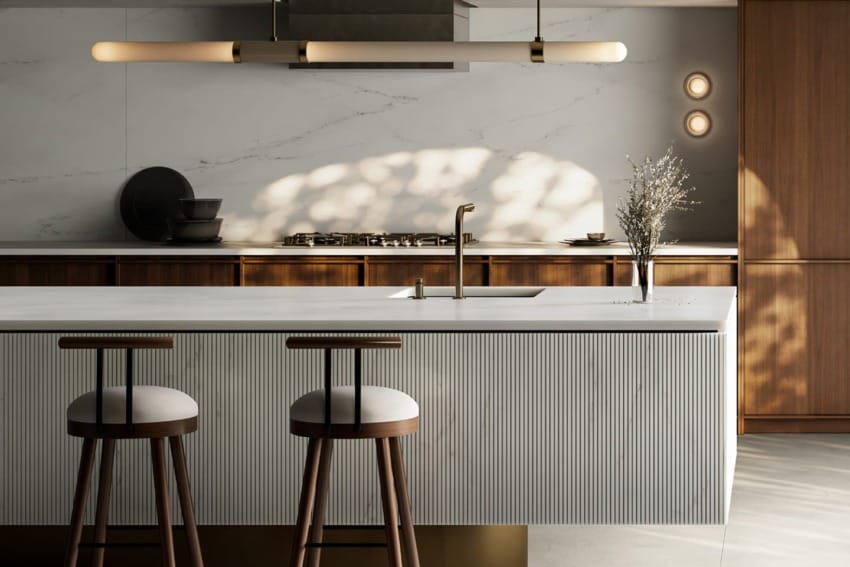 Modern kitchen with white marble countertop, wooden cabinets, two bar stools, and minimalist decor under soft lighting.