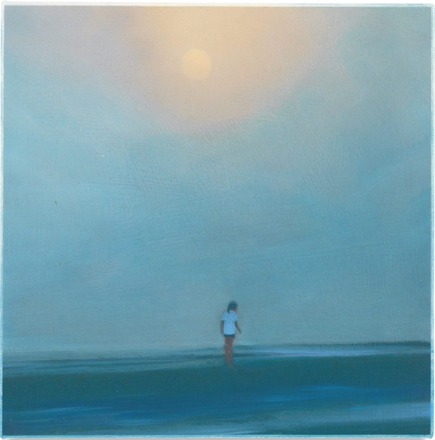 Person standing on a vast, misty beach under a hazy sun, creating a tranquil and contemplative atmosphere.