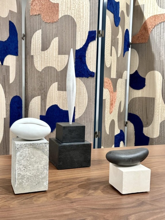 Abstract sculptures on display with geometric patterned backdrop.