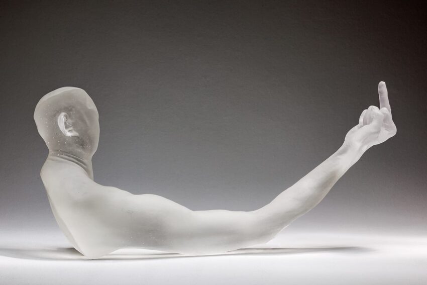 Translucent sculpture of a head and arm with raised middle finger, displayed against a neutral background.