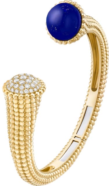 Gold cuff bracelet with textured beading and a round blue stone on one end, diamond-encrusted design on the other end.