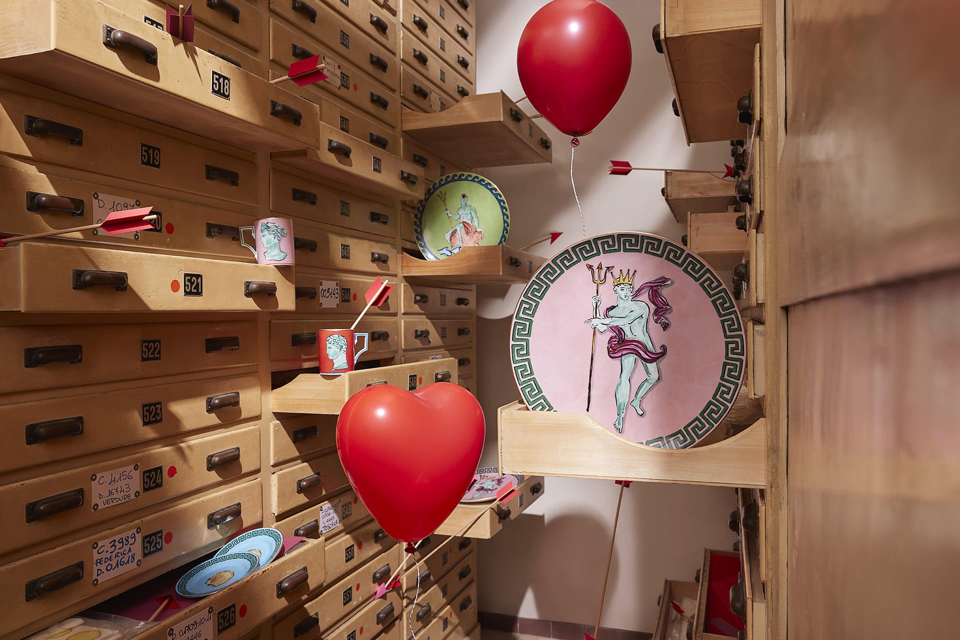 Wooden filing cabinets and shelves with red balloons, plates featuring a dancing horse, and whimsical decorations.