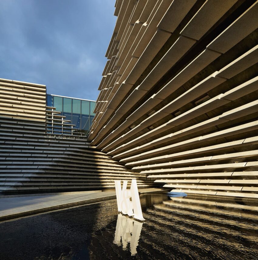 Exterior view of a modern architectural building with angular lines and a reflective water feature in the foreground.