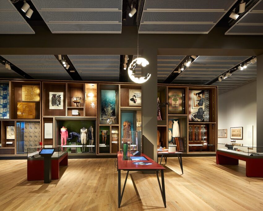 Contemporary art museum exhibit with modern installations, paintings, and sculptures on wooden flooring under soft lighting.