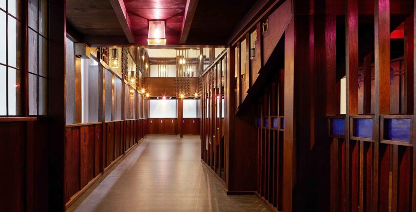 Hallway with warm lighting and wooden paneling, featuring decorative geometric designs and glowing lanterns.
