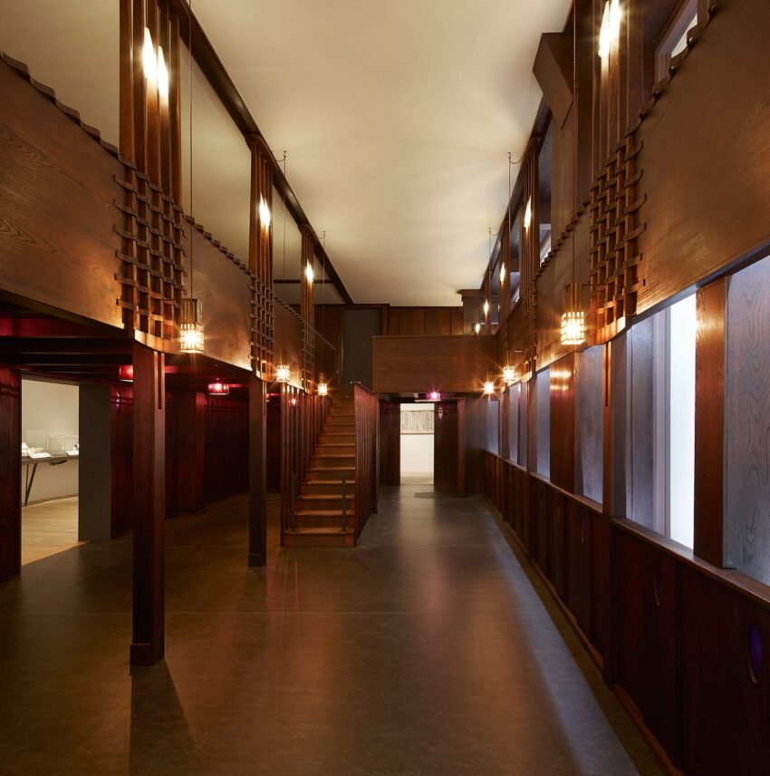 Spacious interior of a building with wooden walls, large windows, and modern lighting fixtures.