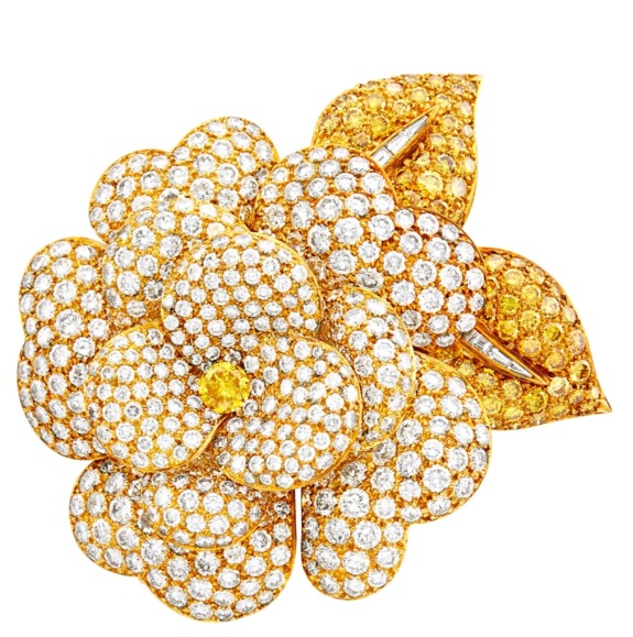 Gold jeweled flower brooch encrusted with sparkling diamonds and a central yellow gemstone, featuring intricate detailing.